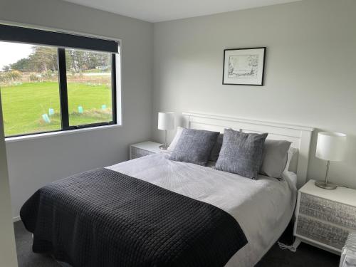 a white bedroom with a bed and a window at Toko Mouth Beach House in Glenledi