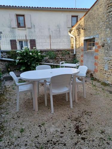 une table et des chaises blanches devant un bâtiment dans l'établissement Gîte Gaïa, calme dans marais Poitevin, à Maillé