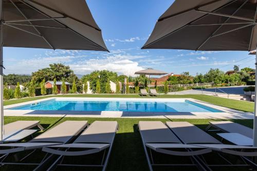 a swimming pool with chairs and an umbrella at O CERVO CHARM HOUSE in Vila Nova de Cerveira