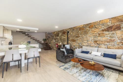 a living room and kitchen with a stone wall at O CERVO CHARM HOUSE in Vila Nova de Cerveira