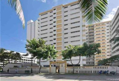 a large building with trees in front of it at Lovely Condo 2 Bedrooms, 2 bathrooms, free 1 Parking at Waikiki Beach in Honolulu