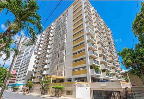 a tall white building with palm trees in front of it at Lovely Condo 2 Bedrooms, 2 bathrooms, free 1 Parking at Waikiki Beach in Honolulu