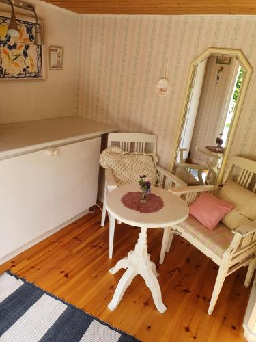 a living room with a table and a couch at Sjönära liten stuga med sovloft, toilet in separate small house, only OUTDOOR shower! in Åkersberga