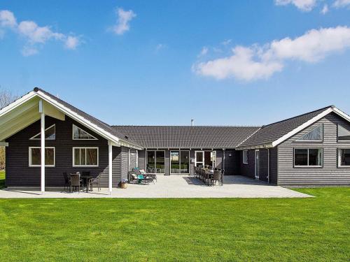 a black house with a patio and grass at 24 person holiday home in Hasselberg in Kappeln
