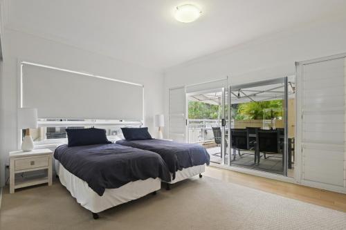 Deep Blue Apartment 1 Tangalooma في تنجالوما: غرفة نوم بيضاء مع سرير ونافذة كبيرة