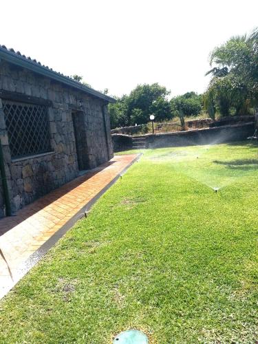 a grassy yard with a stone wall and a building at Il Rustico in Pozzillo