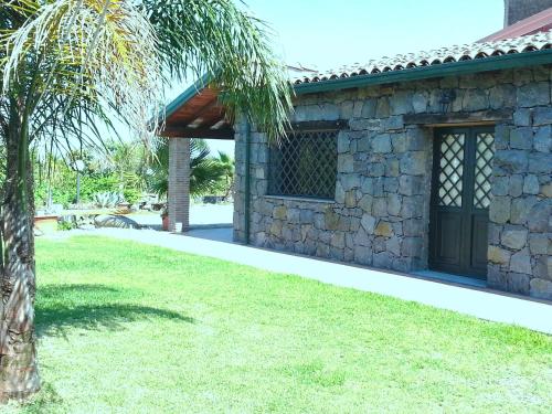 a stone house with a palm tree in the yard at Il Rustico in Pozzillo