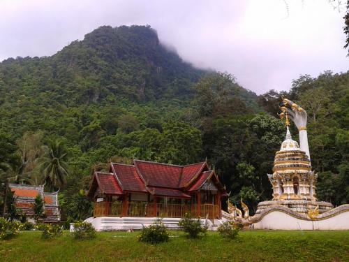 a temple and a building in front of a mountain at Huan Chiang Dao Resort in Chiang Dao