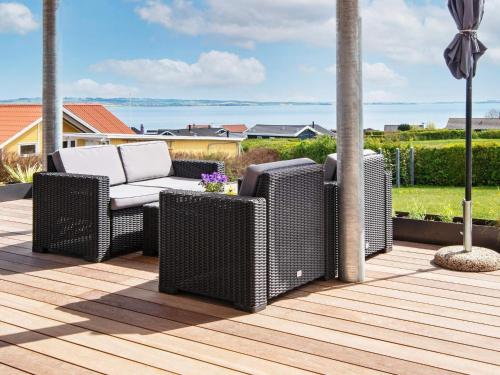 a patio with two wicker chairs on a deck at 6 person holiday home in R nde in Rønde
