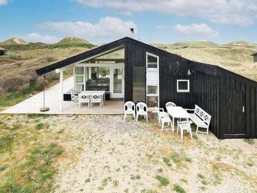 a black and white house with chairs and a table at 8 person holiday home in Pandrup in Blokhus