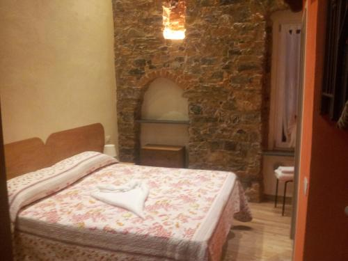 1 dormitorio con 1 cama en una habitación con una pared de piedra en Apartment Camere Cinque Terre Andrea, en La Spezia