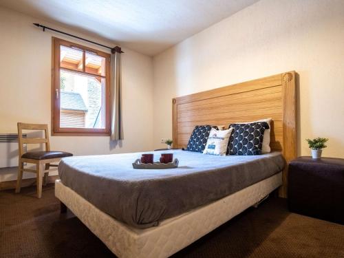 a bedroom with a large bed with a wooden headboard at Appartement Saint-Lary-Soulan, 2 pièces, 6 personnes - FR-1-296-403 in Saint-Lary-Soulan