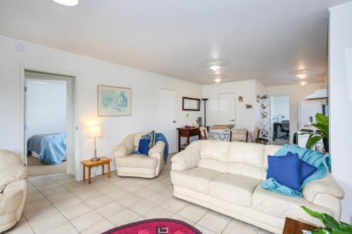 a living room with two white couches and blue pillows at Self Contained Cottage Pukekohe in Auckland