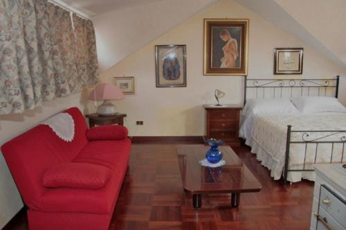 salon z czerwoną kanapą i łóżkiem w obiekcie B&B Domus Gratiae w mieście Ostia