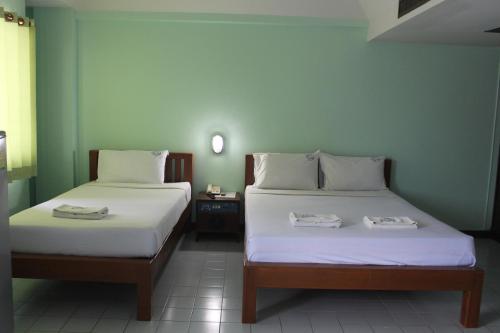 two beds in a small room with two towels on them at Grand Mansion Hotel in Krabi town