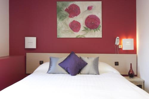 a bedroom with a white bed with purple pillows at Logis Hôtel Duquesne in Nantes
