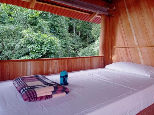 uma cama num quarto de madeira com uma janela em Lodge El Amargal - Reserva Natural, Ecoturismo & Surf em Nuquí