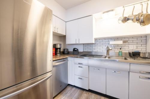 cocina con armarios blancos y nevera de acero inoxidable en Georgetown Villas 2-1c King and Queen Bedrooms ideal for long stays! en Fairview Park