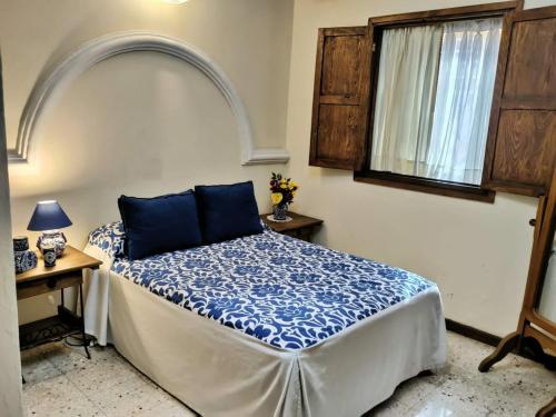 a bedroom with a bed with blue sheets and a window at Villa Sueño Azul B&B in Guanajuato