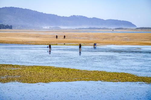 people are standing in the water on a beach at Herons Perch - Meredith Lodging in Netarts