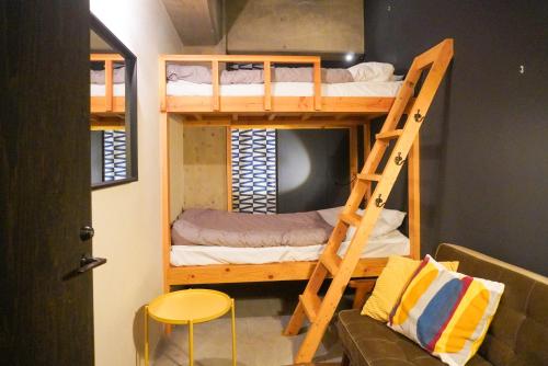 Zimmer mit Etagenbetten mit einer Leiter und einer Couch in der Unterkunft Hostel Niniroom in Kyoto