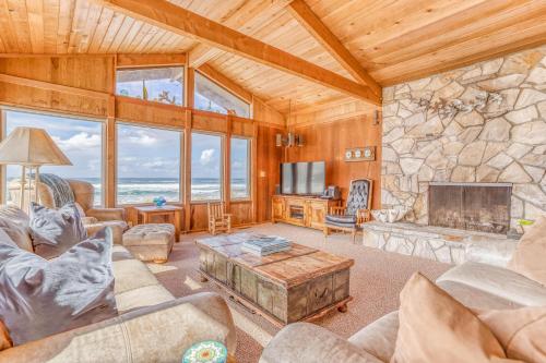 a living room with a large stone fireplace at Nestle Inn - Meredith Lodging in Neskowin