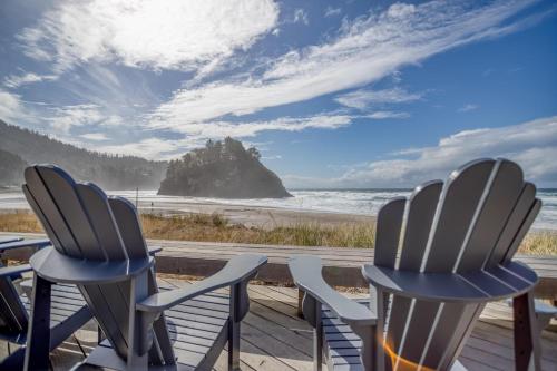 two chairs sitting on a deck looking out at the beach at Nestle Inn - Meredith Lodging in Neskowin