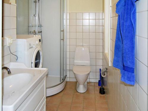 a bathroom with a toilet and a sink and a washing machine at Holiday home VANKIVA in Vankiva