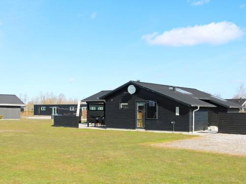 a black house on a field with a grass at 8 person holiday home in Hadsund-By Traum in Hadsund
