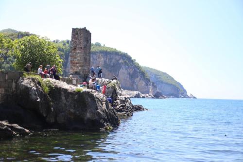 a group of people sitting on the rocks near the water at bedesten otel in Amasra