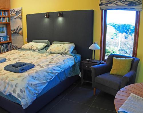 um quarto com uma cama, uma cadeira e uma janela em Kotare BandB em Geraldine
