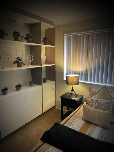 a bedroom with a bed and a lamp on a table at Flat Bush Holiday Accomodation in Auckland