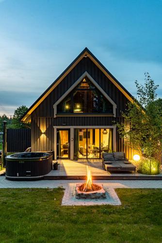a large house with a fire pit in the yard at SOPRANO - 'Virš Ąžuolų' - Forest SPA - FREE jacuzzi in Paplatelė