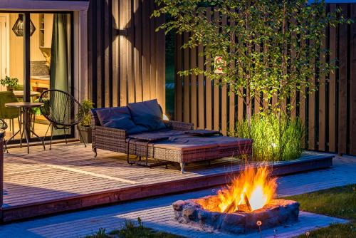 a patio with a couch and a fire pit at SOPRANO - 'Virš Ąžuolų' - Forest SPA - FREE jacuzzi in Paplatelė