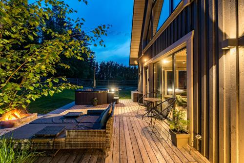 a wooden deck with a fireplace on a house at SOPRANO - 'Virš Ąžuolų' - Forest SPA - FREE jacuzzi in Paplatelė