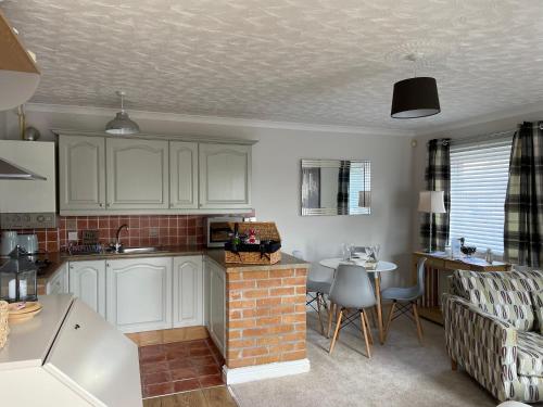 a kitchen with white cabinets and a living room at The Cwtch - a self contained one bedroom annex in Pwllheli
