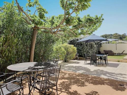 a patio with tables and chairs and an umbrella at F2 avec jacuzzi, pétanque, à 3 min mer, dans grande propriété in Porticcio