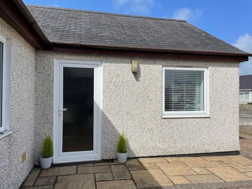 a house with a door and two potted plants at The Cwtch - a self contained one bedroom annex in Pwllheli