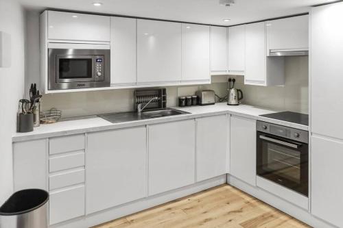 a white kitchen with a sink and a microwave at Cosy 1-BDR w/ free parking in central Reading in Reading