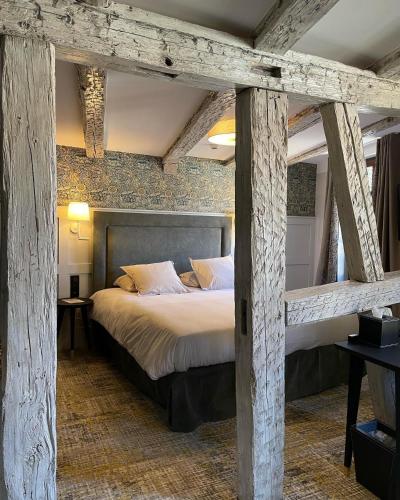 - une chambre avec un grand lit et des poutres apparentes dans l'établissement Logis Hôtel-Restaurant du Mouton, à Ribeauvillé