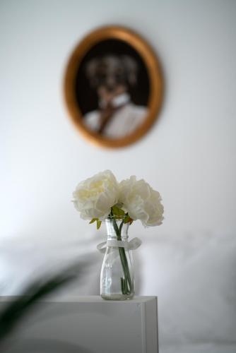un vase de fleurs blanches sur une table avec un miroir dans l'établissement LITTLE MAMA including a parking space at 100 meters, à Colmar