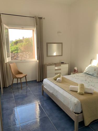 a bedroom with a bed and a chair and a window at L'oasi di Pace in Pantelleria