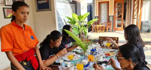 a group of people sitting at a table eating food at Villa Jackson in Tejakula