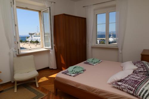 a bedroom with a bed and a chair and windows at Apartman DAJANA in Supetar