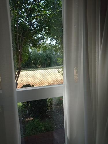 a window with a white curtain and a view of a field at La Casa di Tara B&B Armonia e Natura in Recanati