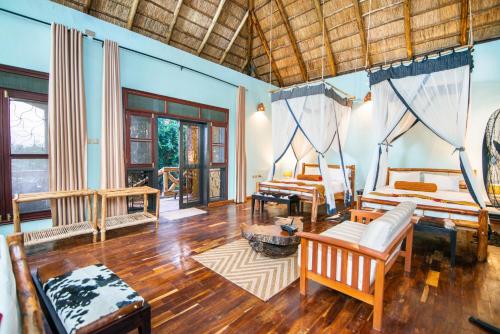 a living room with two beds and a wooden floor at Buffalo Safari Lodge in Katunguru