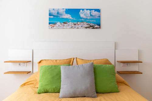 ベヘール・デ・ラ・フロンテーラにあるapartamentos Martin Roioのベッドルーム1室(緑と白の枕が備わるベッド1台付)