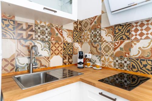 ベヘール・デ・ラ・フロンテーラにあるapartamentos Martin Roioのタイル張りの壁、シンク付きのキッチン