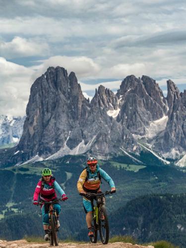 two people riding bikes on top of a mountain at Kedul Lodge in Santa Cristina in Val Gardena
