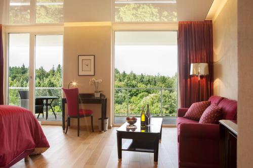 ein Wohnzimmer mit einem roten Sofa und einem Tisch in der Unterkunft Schwitzer's Hotel am Park in Waldbronn